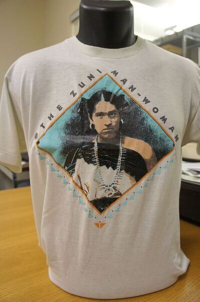 White tee-shirt with "Zuni Man-Woman" written around an image of a Two-Spirit person in a diamond