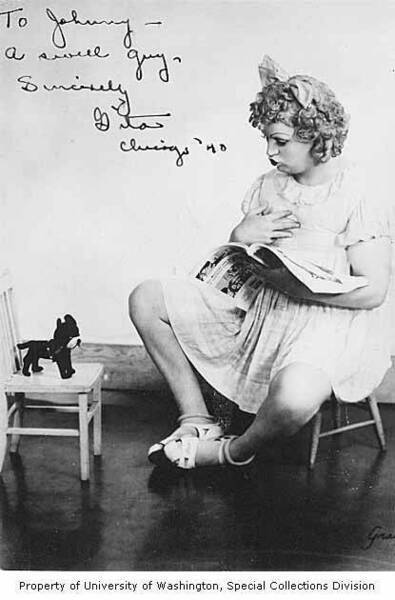 Download the full-sized image of Gita Gilmore dressed as a young girl, sitting on a small chair and reading to a stuffed dog