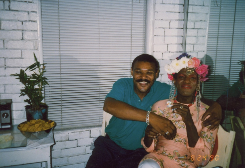 Download the full-sized image of A Photograph of Marsha P. Johnson at Her Birthday Party, Sitting Next to a Friend Whose Arm is Wrapped Around Her