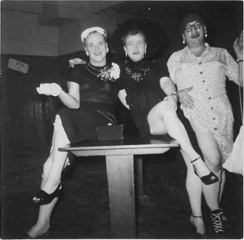 Download the full-sized image of Three unknown femmes sitting and standing in a basement