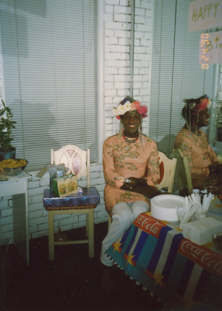 Download the full-sized image of A Photograph of Marsha P. Johnson Sitting in a Chair in Front of a Mirror at Her Birthday Party