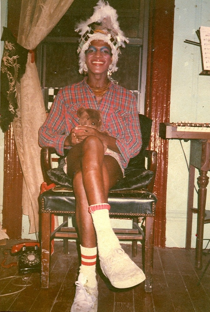 Download the full-sized image of A Photograph of Marsha P. Johnson Sitting in a Chair Holding a Teddy Bear