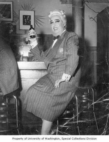 Download the full-sized image of Rae Bourbon in skirt suit, sitting at a bar