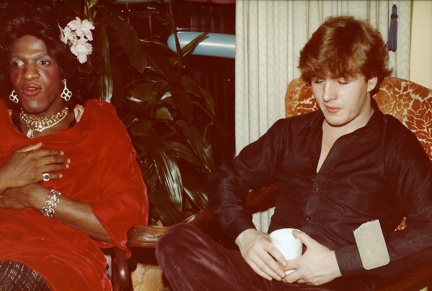 Download the full-sized image of A Photograph of Marsha P. Johnson Sitting with Another Person, Wearing a Red Dress and Floral Hair Clip