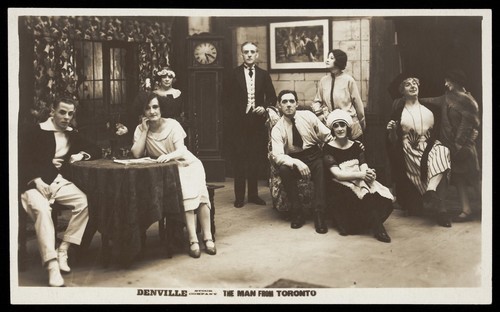Download the full-sized image of Actors, one in drag, performing "The man From Toronto", pose on set for a group portrait. Photographic postcard, 192-.