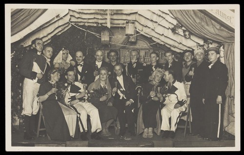 Download the full-sized image of German actors, some in drag, gather on stage at a party. Photographic postcard, 1930-45.