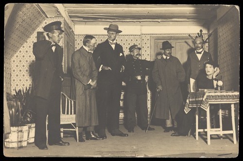 Download the full-sized image of French or Belgian prisoners of war, one in drag, performing a scene from "L'anglais tel qu'on le parle" at Friedberg Camp, Germany. Photographic postcard, 1917.