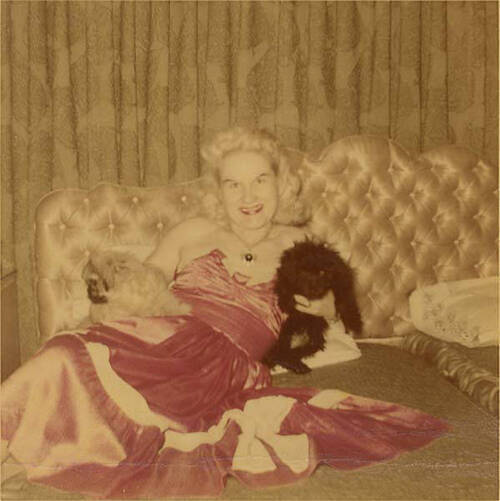 Download the full-sized image of Unknown femme lounging on bed holding two dogs
