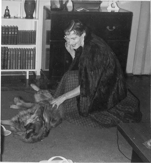 Download the full-sized image of Unknown femme in fur coat crouched petting dog